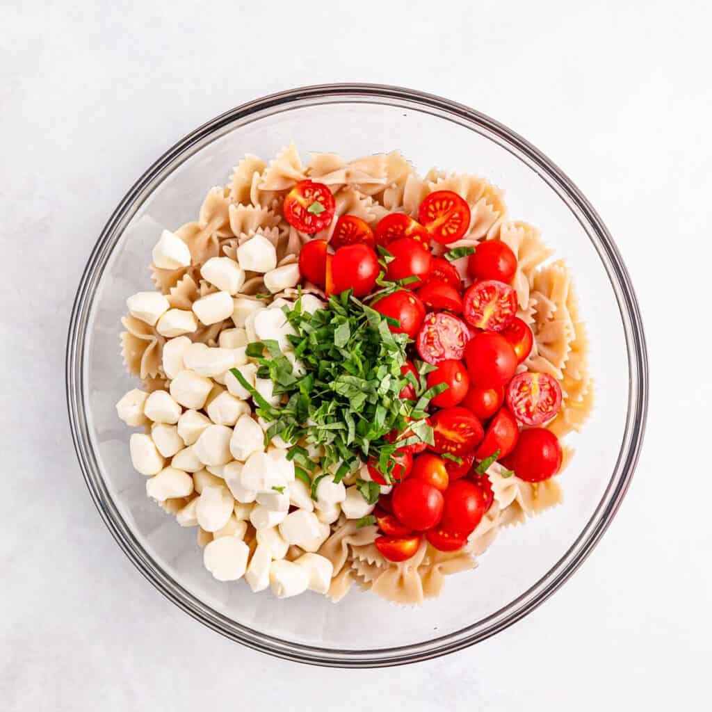 caprese pasta salad ingredients in glass bowl before mixing