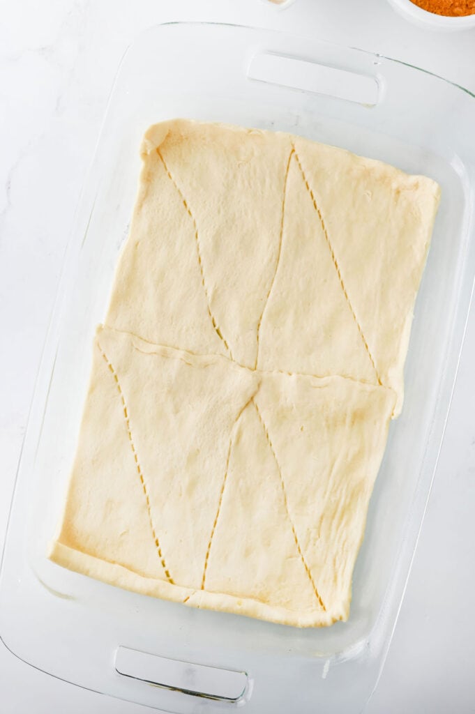 crescent roll dough in bottom of a glass casserole dish