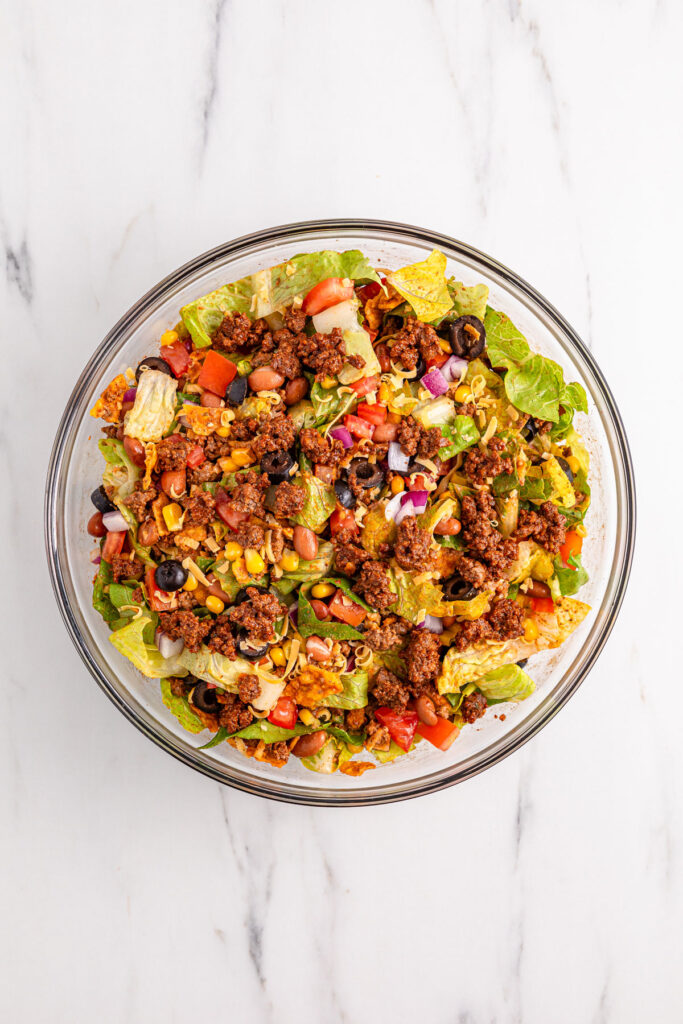 mixing Doritos taco salad in glass bowl