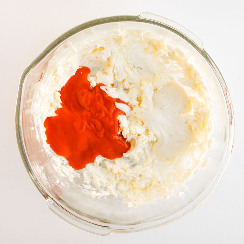 cream cheese and buffalo sauce in glass bowl