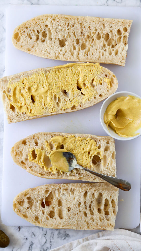 spreading mustard on baguette