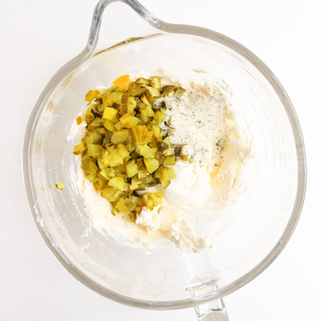 mixing dill pickle dip ingredients in glass bowl