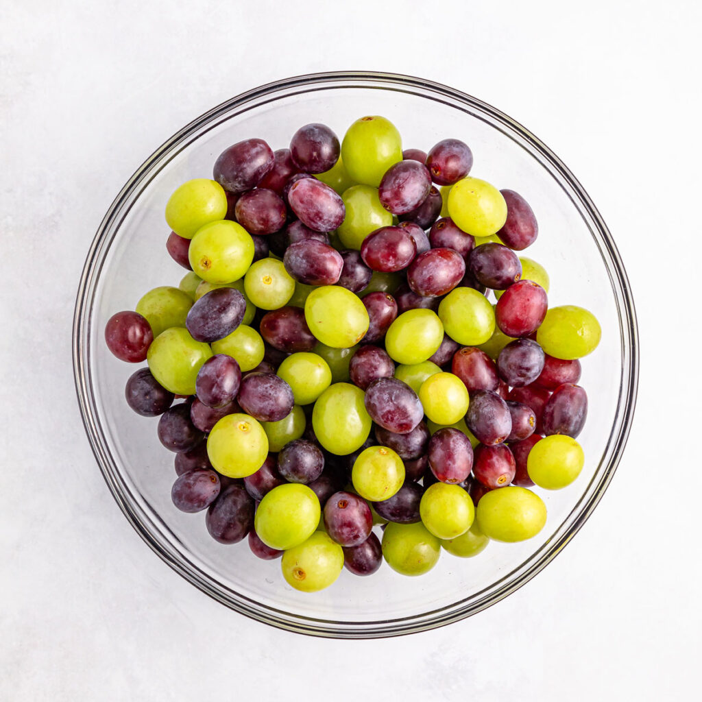 green and purple grapes in glass bowl