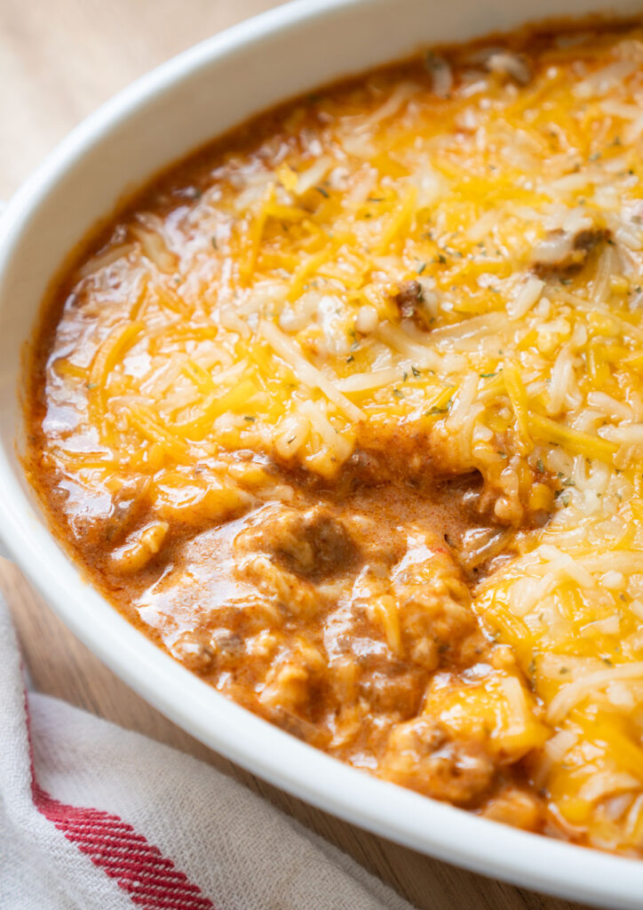 enchilada dip in white dish with a scoop removed