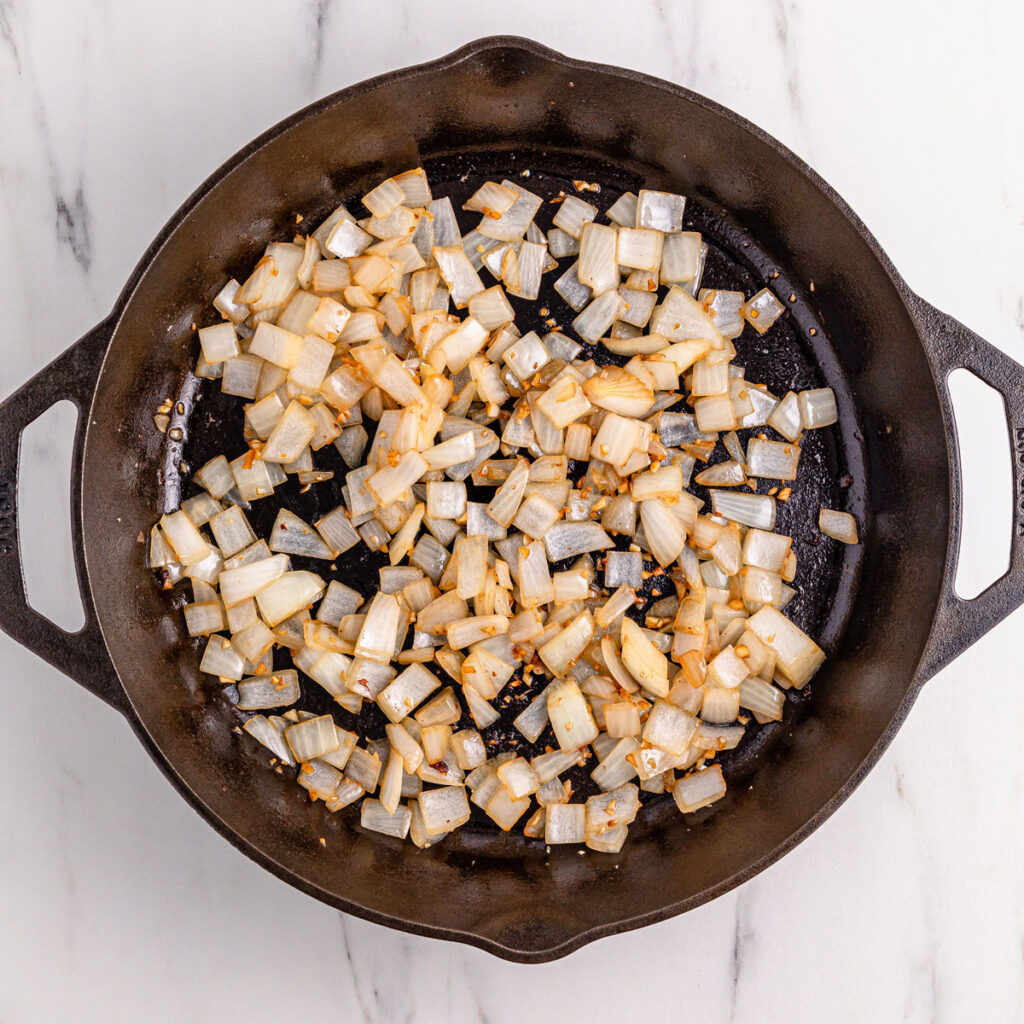 onions cooking in cast iron pan for black pepper chicken