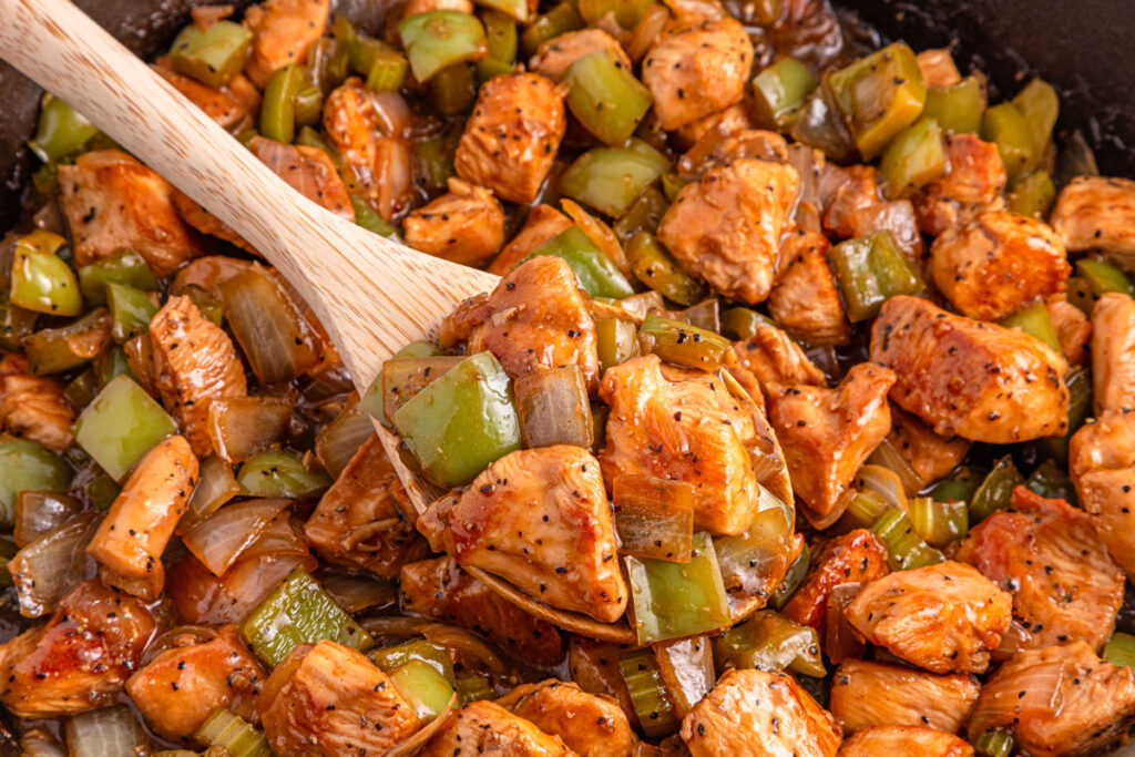 wooden spoon scooping black pepper chicken