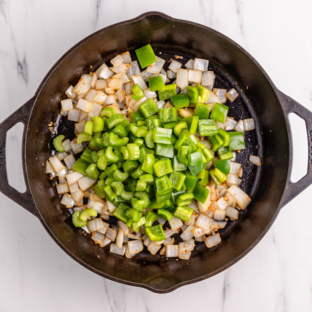 chopped onion and bell pepper in cast iron skillet for black pepper chicken