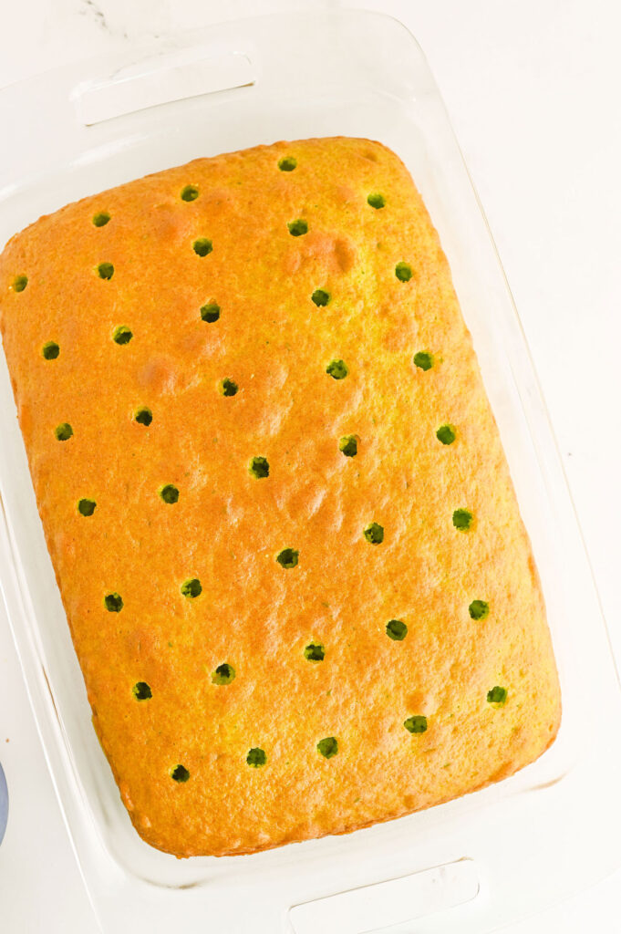 holes poked in green cake to make grinch poke cake