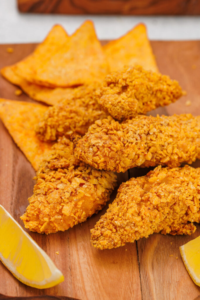 Doritos chicken tenders on cutting board with chips in background