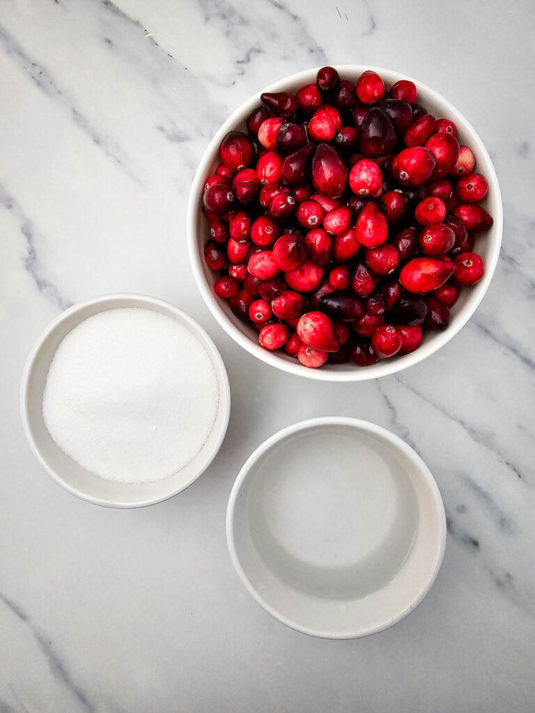 cranberries, sugar, and water in bowls on countertop for making cranberry sauce