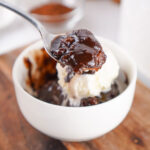 spoon holding chocolate cobbler with vanilla ice cream