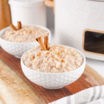 two bowls of slow cooker rice pudding in front of crock pot
