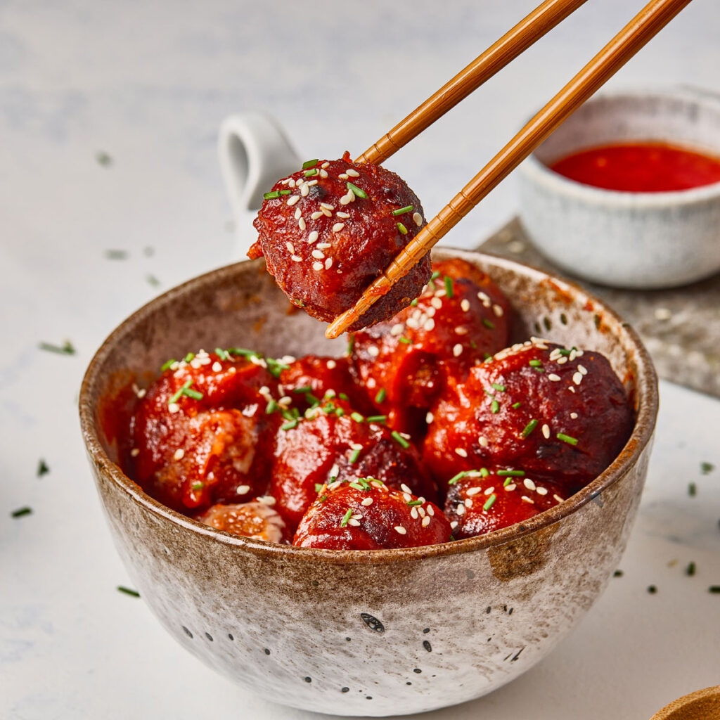chopsticks lifting korean meatball from bowl