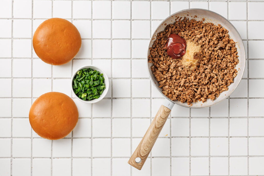 pan with korean sloppy joes in it with bun and toppings nearby