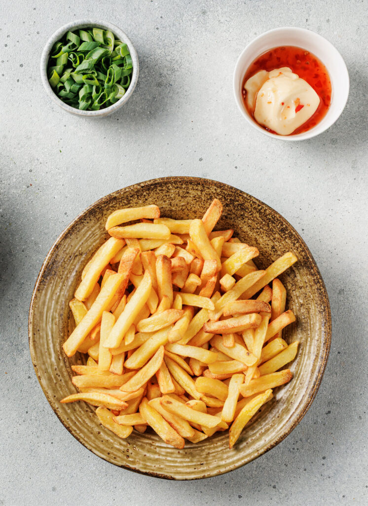 fries on plate with bowls of green onion and korean sauce