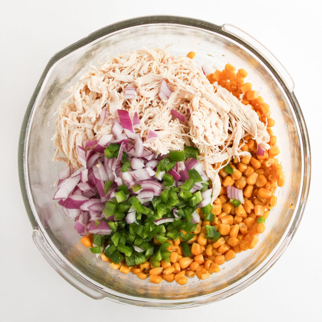 street corn chicken salad ingredients in glass bowl
