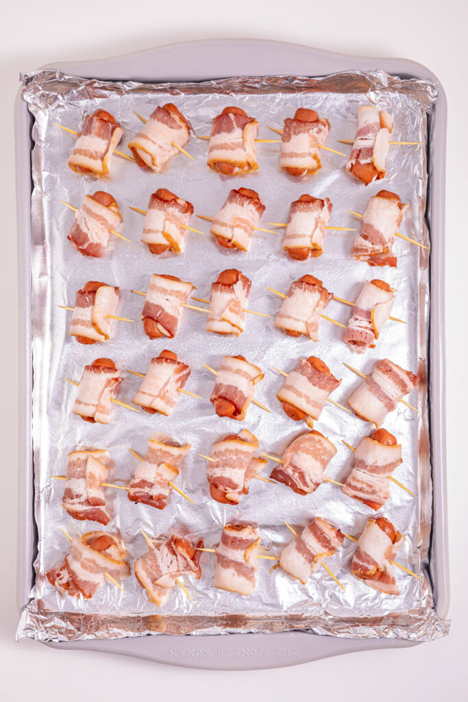 bacon wrapped little smokies before cooking on baking sheet