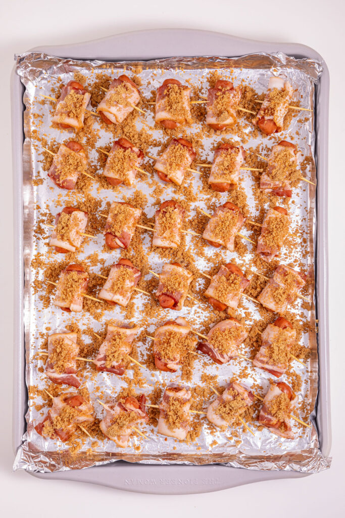bacon wrapped little smokies sprinkled with brown sugar on cookie sheet before baking