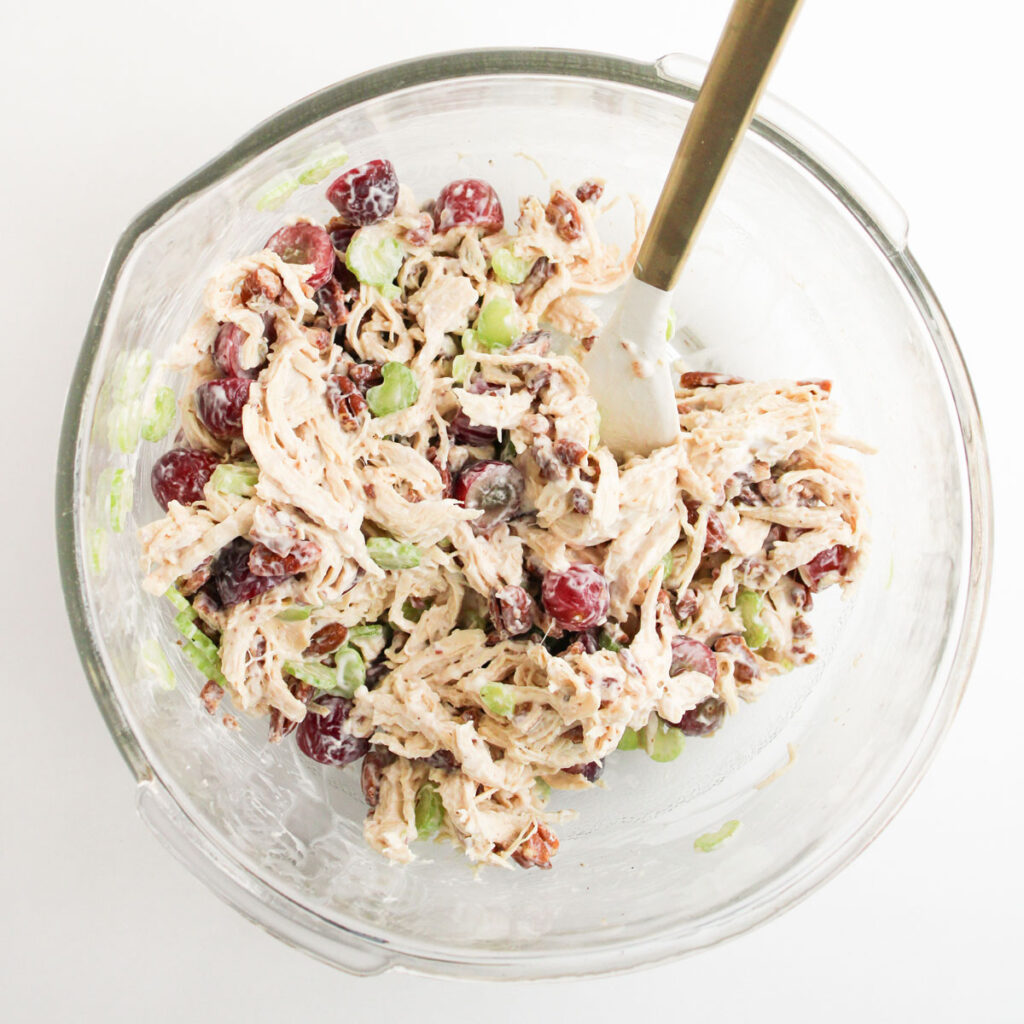 mixing chicken salad in glass bowl