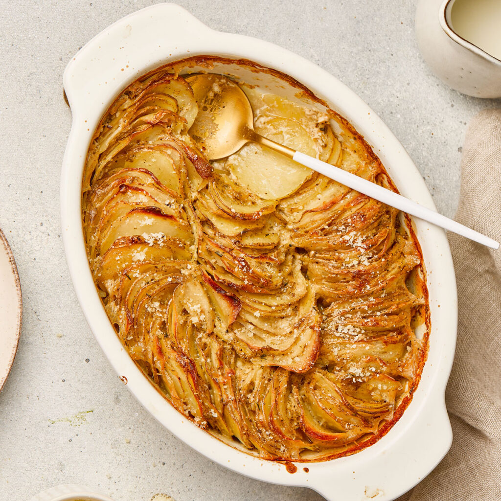 scallop potatoes in white baking dish with spoon