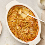 scallop potatoes in white baking dish with spoon