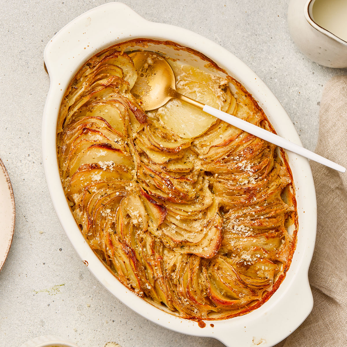 scallop potatoes in white baking dish with spoon