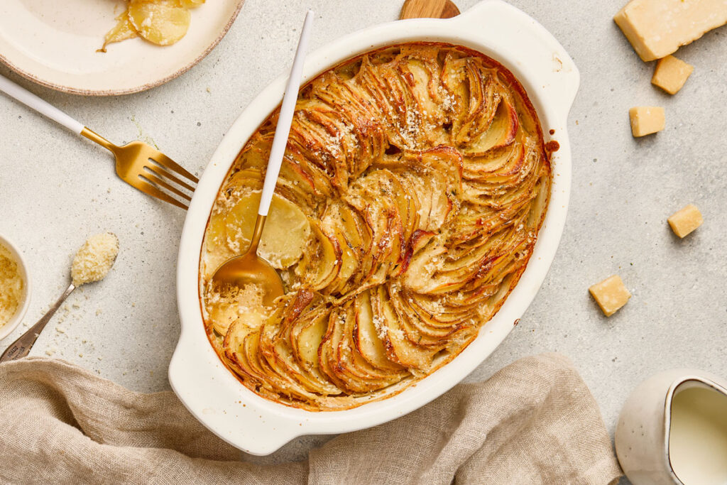 scallop potatoes in white baking dish with spoon